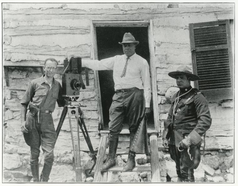 Filmmaker Oscar Micheaux standing next to a camera