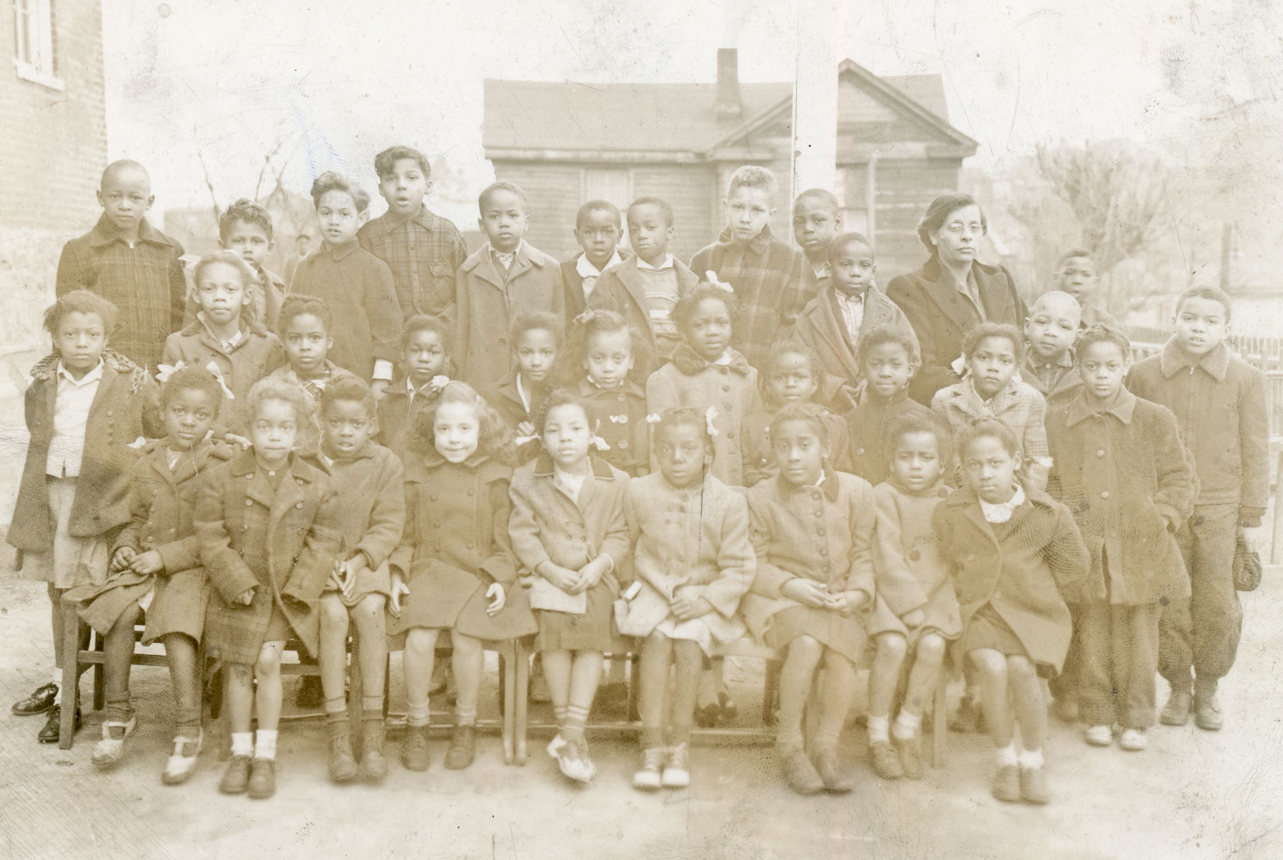 Students in peacoats sit and stand in a photo of their class