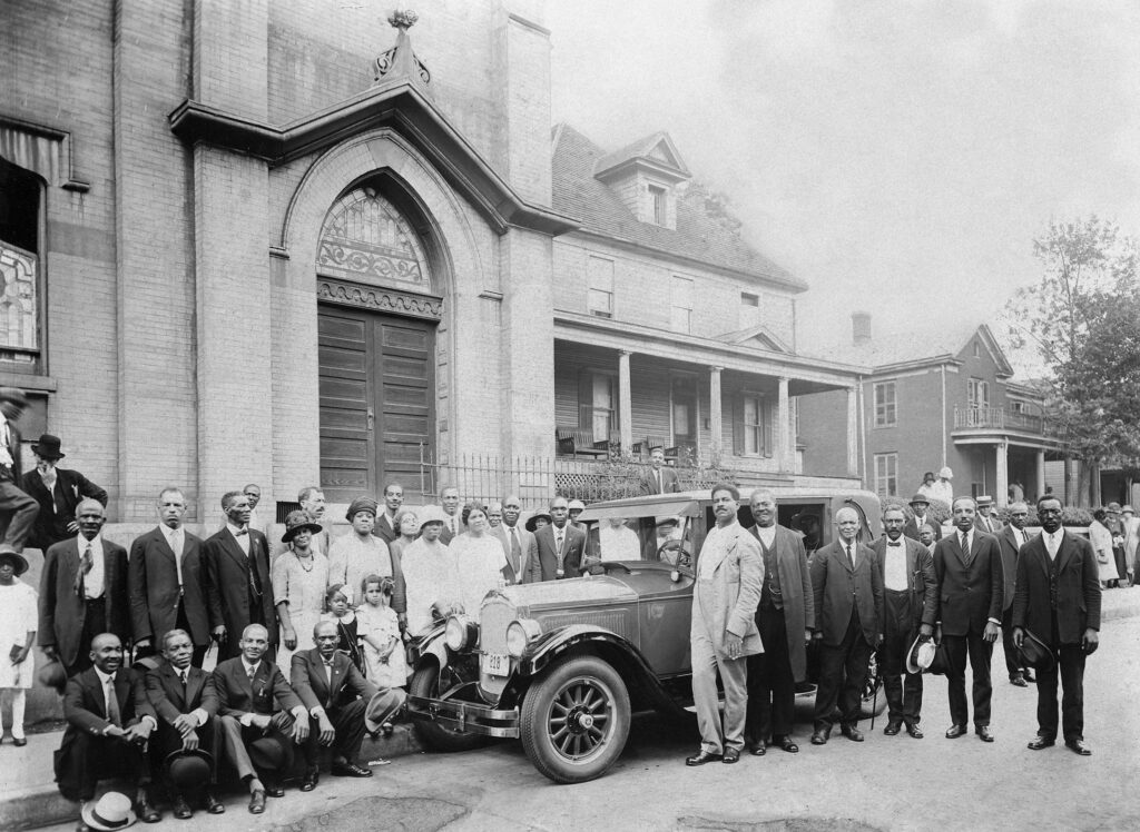 A large group of congregants and a nice car out front of High Street Baptsist.